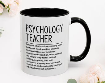 May include: A white Psychology Teacher mug with a black interior and handle. The mug features the text "PSYCHOLOGY TEACHER" in bold black letters, along with a definition of a psychology teacher. The mug is surrounded by white flowers.