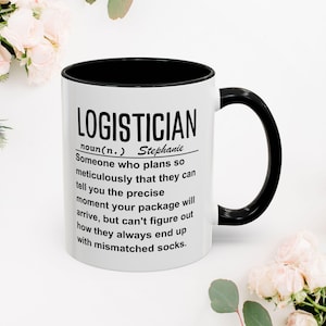 May include: White ceramic mug with a black rim and handle. The mug has a black graphic that reads "LOGISTICIAN noun (n.) Stephanie Someone who plans so meticulously that they can tell you the precise moment your package will arrive, but can't figure out how they always end up with mismatched socks."