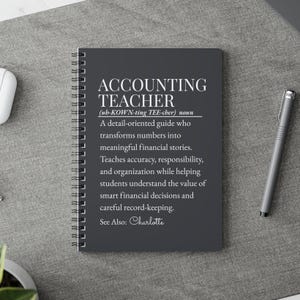 May include: A dark gray spiral-bound notebook featuring white text that reads: ACCOUNTING TEACHER (ub-KOWN-ting TEE-cher) noun. A detail-oriented guide who transforms numbers into meaningful financial stories. Teaches accuracy, responsibility, and organization.