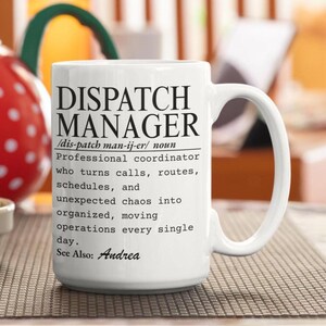 May include: A white ceramic mug featuring black printed text that defines a Dispatch Manager as a professional coordinator who turns calls, routes, schedules, and unexpected chaos into organized, moving operations every single day. See Also: Andrea.