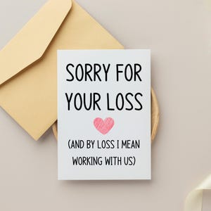 May include: A white greeting card with black text that reads SORRY FOR YOUR LOSS (AND BY LOSS I MEAN WORKING WITH US) and a small pink hand-drawn heart in the center, accompanied by a light tan envelope positioned behind the card.