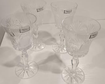 May include: Four clear crystal wine glasses with intricate etched designs. Each glass features a flared bowl, a faceted stem, and a starburst base. The glasses have a label that reads "Robbe & Berking, GERMANY, CRYSTAL".