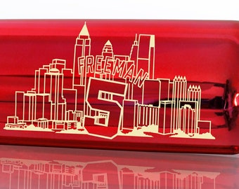 May include: A red baseball bat with a gold inscription commemorating Freddie Freeman's 2021 Division Series winning home run. The inscription reads "Freddie Freeman #5 2021 Division Series Final At-Bat Series Winning Home Run Atlanta-3 Games Milwaukee-1 Game".