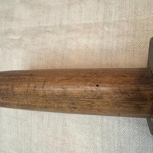 Pu&ograve; includere: Un primo piano di un mattarello di legno con una superficie liscia e marrone. Il mattarello ha un manico leggermente arrotondato ed &egrave; fatto di un unico pezzo di legno.