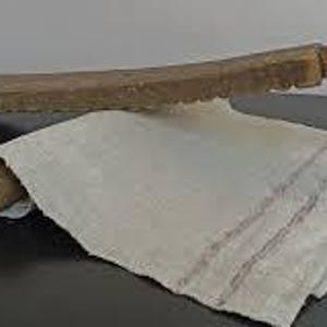 Pu&ograve; includere: Due palette di legno con manico marrone e una lama lunga e piatta. Le lame hanno un bordo seghettato. Le palette sono incrociate su un panno di lino bianco.
