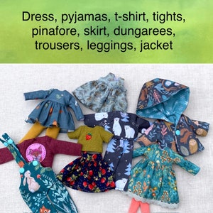 Könnte beinhalten: Eine Sammlung von Miniatur-Puppenkleidern, darunter ein Kleid, ein Pyjama, ein T-Shirt, Strumpfhosen, ein Latzkleid, ein Rock, eine Latzhose, eine Hose, Leggings und eine Jacke. Die Kleidung ist aus verschiedenen Stoffen gefertigt und hat unterschiedliche Muster und Farben.
