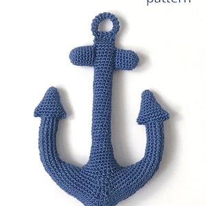 May include: A blue crocheted anchor with a loop at the top. The anchor is a handmade amigurumi toy. The text "Anchor pattern" is above the anchor and the text "@Ludasamigurumi" is below the anchor.