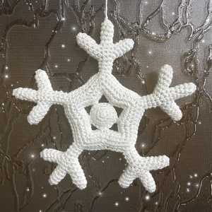 May include: A white, crocheted snowflake ornament with six symmetrical arms and a central sphere. The snowflake is suspended by a thin white string, perfect for holiday decor. The background is a textured, dark surface with sparkling accents.
