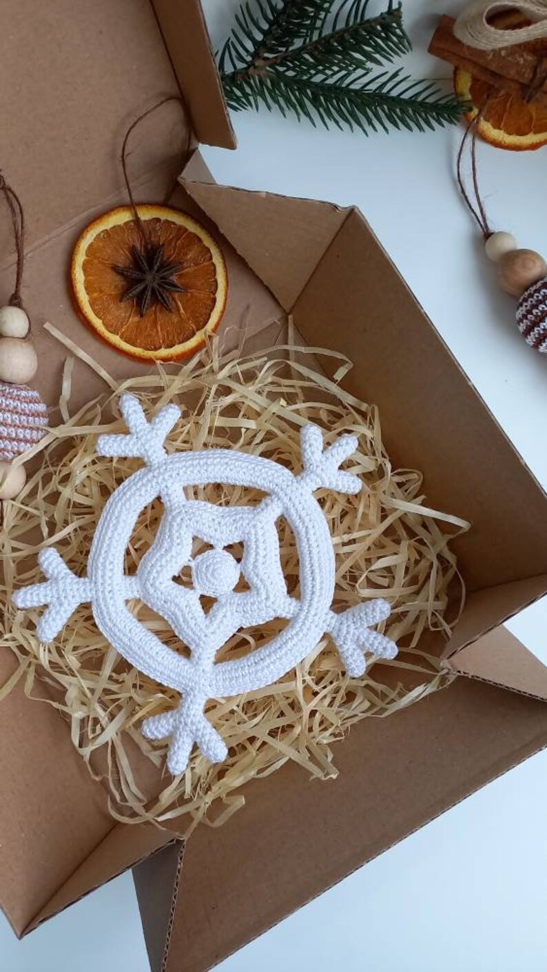 May include: A white crocheted snowflake ornament in a cardboard box with shredded paper.