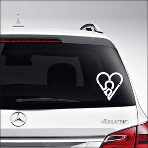 May include: White vinyl decal of a heart with the letters "CA" inside, applied to the rear window of a silver car.