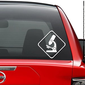 May include: A white microscope icon inside a white diamond shape on a red car window.