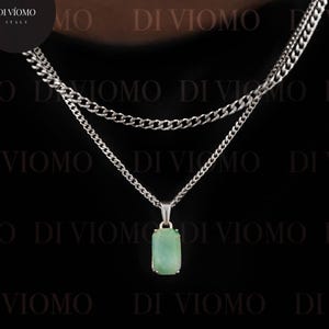 May include: A layered silver-tone chain necklace featuring a rectangular light green stone pendant. The necklace consists of two distinct chains of varying lengths, with the pendant suspended from the longer chain. The text DI VIOMO is visible.