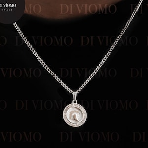 May include: A silver chain necklace with a circular pendant. The pendant features a detailed design. The necklace is displayed against a black background with the brand name "DIVIOMO" repeated. The website address www.diviomo.com is also visible.