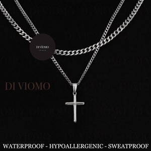 Puede incluir: Un collar de cadena de plata con un colgante de cruz de plata. El collar está formado por dos cadenas de diferentes grosores. El texto "DI VIOMO" aparece varias veces en la imagen. Los textos "WATERPROOF - HYPOALLERGENIC - SWEATPROOF" y "WWW.DIVIOMO.COM" también son visibles.