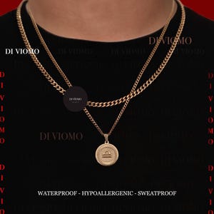 May include: A gold-toned layered chain necklace featuring a circular pendant with an engraved Libra zodiac symbol. The piece includes the text DI VIOMO and the words WATERPROOF - HYPOALLERGENIC - SWEATPROOF printed at the bottom of the image.