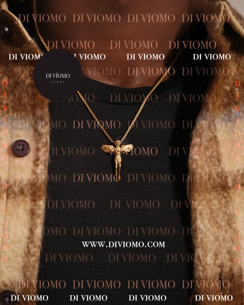 Puede incluir: Un collar de cadena dorada con un colgante que presenta una figura de &aacute;ngel alado. El collar lo lleva una persona que lleva una camisa negra con el texto "DI VIOMO" repetido en blanco.