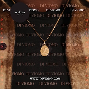 May include: A gold chain necklace with a round pendant featuring a religious image. The necklace is worn by a person wearing a black shirt with the text "DI VIOMO" repeated in a pattern. The text "WWW.DIVIOMO.COM" is also visible on the shirt.
