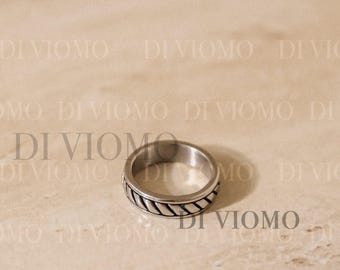 May include: A silver-toned metal ring featuring a central band with a diagonal rope-like twisted texture. The ring has smooth, polished edges on both the top and bottom, creating a clean, circular profile. The surface has a metallic sheen.