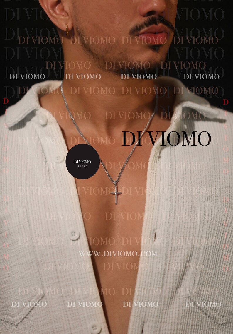 May include: A person wearing a white shirt with a silver chain necklace and a small cross pendant. The necklace has a black tag with the text "DIVIOMO ITALY" on it. The background is a white and black pattern with the text "DI VIOMO" repeated.