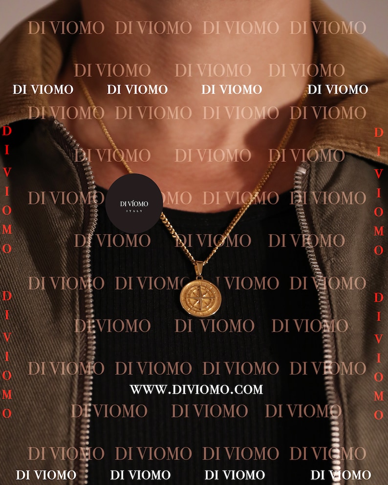 May include: A gold chain necklace with a compass pendant. The necklace is worn by a person wearing a brown jacket. The text "DI VIOMO ITALY" is visible on the pendant.