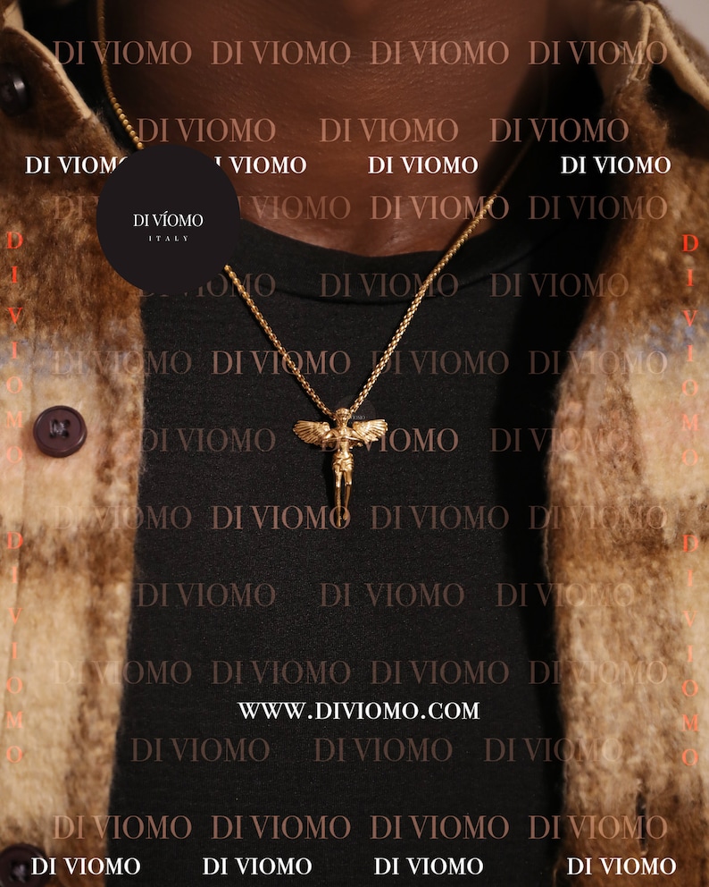 May include: A gold chain necklace with a pendant featuring a winged angel figure. The necklace is worn by a person wearing a black shirt with the text "DI VIOMO" repeated in white.