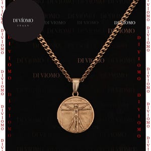 Könnte beinhalten: Eine goldene Kettenkette mit einem Anhänger, der eine goldfarbene Darstellung des Vitruvianischen Menschen zeigt, eine berühmte Zeichnung von Leonardo da Vinci. Der Anhänger ist mit "DI-VIOMO 1902 ITALIEN" beschriftet.