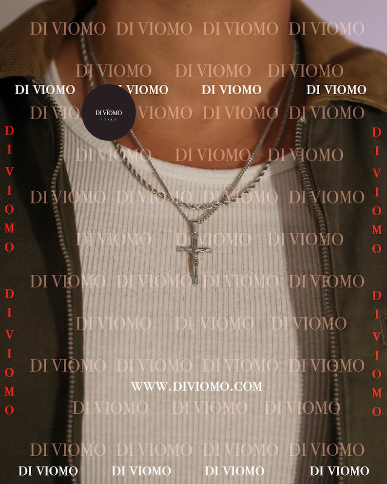 Puede incluir: Un hombre con una camisa blanca con un collar de cadena de plata y un colgante de cruz de plata. El collar est&aacute; superpuesto con una segunda cadena. El fondo es una chaqueta verde con el texto "DI VIOMO" repetido.