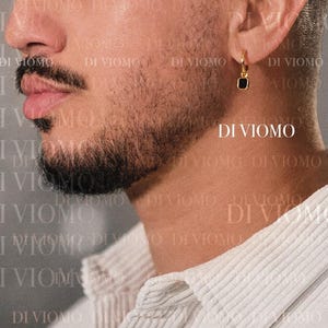 May include: A gold hoop earring featuring a small, square-shaped black stone pendant. The earring is worn on the earlobe. The text DI VIOMO is visible in the image, appearing multiple times as a watermark overlay across the entire composition.