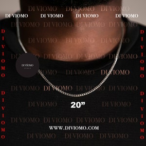 Puede incluir: Un collar de cadena de plata sobre un fondo negro. La cadena tiene 50,8 cm de largo y un dise&ntilde;o de eslabones de cadena. El texto "DI VIOMO" se repite en un patr&oacute;n en el fondo. La direcci&oacute;n del sitio web "www.diviomo.com" tambi&eacute;n se incluye en la imagen.