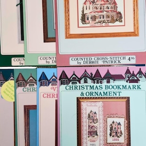 May include: A collection of cross-stitch patterns and Christmas ornaments. The patterns feature detailed images of Victorian houses, some framed and others as bookmarks. The text includes "Christmas 1995" and "Christmas Bookmark & Ornament".
