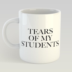 Könnte beinhalten: Weiße Keramik-Kaffeetasse mit schwarzem Text, der "Tears of my students" lautet.