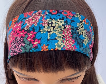 May include: A black headband with a colorful floral print. The print features pink, blue, yellow, and orange flowers on a black background.