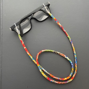 May include: Black eyeglasses with clear lenses and a floral patterned eyeglass chain.