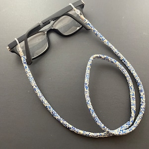 May include: A pair of black eyeglasses with a white and blue floral patterned eyeglass chain.