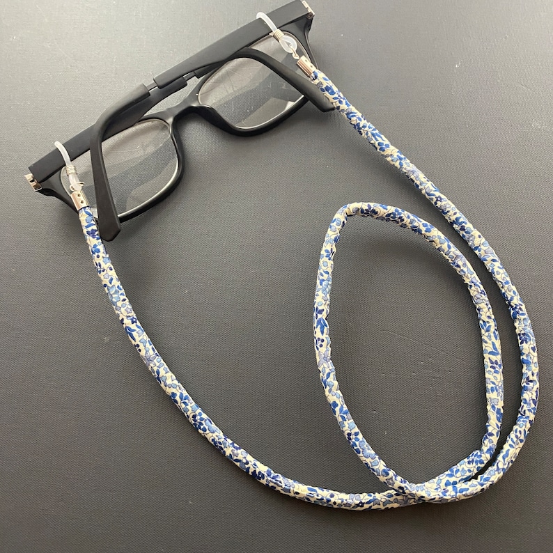 May include: A pair of black eyeglasses with a white and blue floral patterned eyeglass chain.