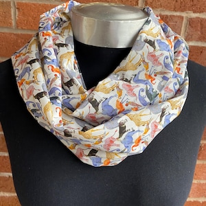 May include: A white silk scarf with a colorful print of various animals, including giraffes, elephants, and birds.