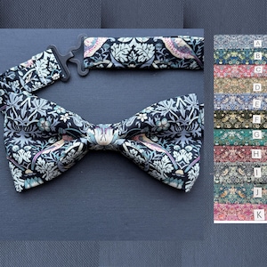 May include: A black bow tie with a floral pattern in shades of blue, gray, and pink. The adjustable neckband and clasp are visible. A color chart with various fabric patterns is on the right.