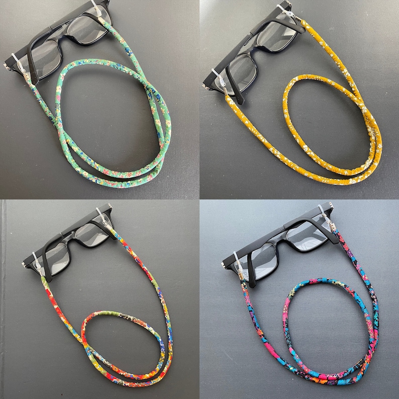 May include: Four pairs of glasses with different patterned eyeglass chains. The chains are made of fabric and feature floral patterns in green, yellow, red, and blue.