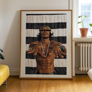 May include: A framed art print depicting a man with long hair, a headband, and a necklace. The background features black and white stripes. The man is shirtless with his arms outstretched.