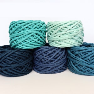 May include: Five balls of yarn in shades of blue and green. The yarn is a thick, chunky style, perfect for crocheting or knitting.