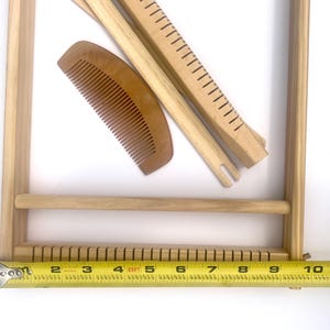 Pode incluir: Um tear de madeira com um pente, duas ferramentas de tecelagem e um pente de madeira. O tear tem aproximadamente 25 cm de largura. As ferramentas s&atilde;o castanhas claras e parecem n&atilde;o utilizadas. O tear &eacute; projetado para projetos de tecelagem.