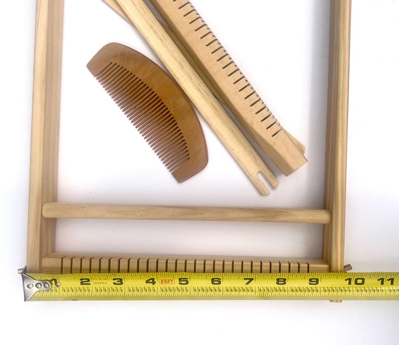 Pode incluir: Um tear de madeira com um pente, duas ferramentas de tecelagem e um pente de madeira. O tear tem aproximadamente 25 cm de largura. As ferramentas s&atilde;o castanhas claras e parecem n&atilde;o utilizadas. O tear &eacute; projetado para projetos de tecelagem.