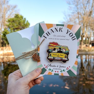 May include: A thank you card with a colorful design featuring a cartoon car with a couple inside. The card says "Thank You" and "For celebrating with us on our special day!" with the names "Amelie & James" and the date "23.08.2024".