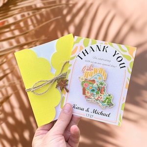 May include: A yellow scalloped-edge card tied with twine and a wooden palm tree charm, next to a thank you card. The thank you card has a colorful Oahu, Hawaii pin and text that reads "Thank You" and "Kara & Michael 1.7.27".