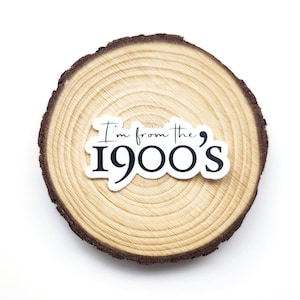 May include: A white sticker with black text on a wooden round slice. The text reads "I'm from the '900's".