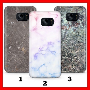 Puede incluir: Tres fundas para teléfono con diferentes patrones de mármol. La primera funda es gris con vetas blancas, la segunda funda es blanca con vetas azules y moradas, y la tercera funda es gris con vetas negras.