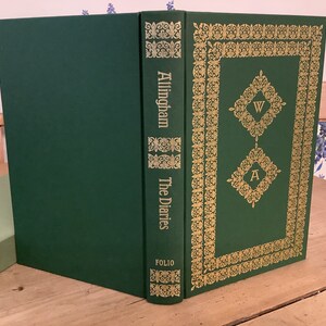 Puede incluir: Un libro de tapa dura verde con letras doradas en el lomo que dice "Allingham The Diaries Folio". La portada tiene un borde decorativo dorado con las letras "W" y "A" en el centro.