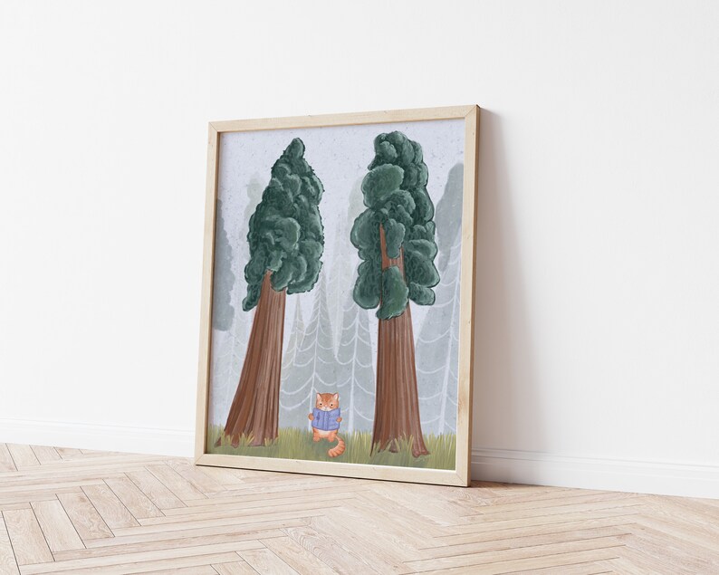 May include: A framed illustration of two large trees with a small orange cat wearing a blue sweater standing in front of them. The trees are brown with green foliage and the background is a light gray.