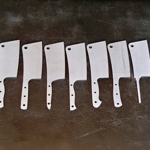 May include: Eight silver metal knife blanks, laid out in a row on a dark grey surface. The blanks are all the same shape, but vary slightly in size.