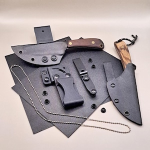 Może przedstawiać: Zestaw czarnych skórzanych pochw na noże z czarnym plastikowym klipsem do paska, srebrnym łańcuszkiem i dwoma nożami z drewnianymi rękojeściami. Jeden nóż ma czarne ostrze, a drugi brązowe.